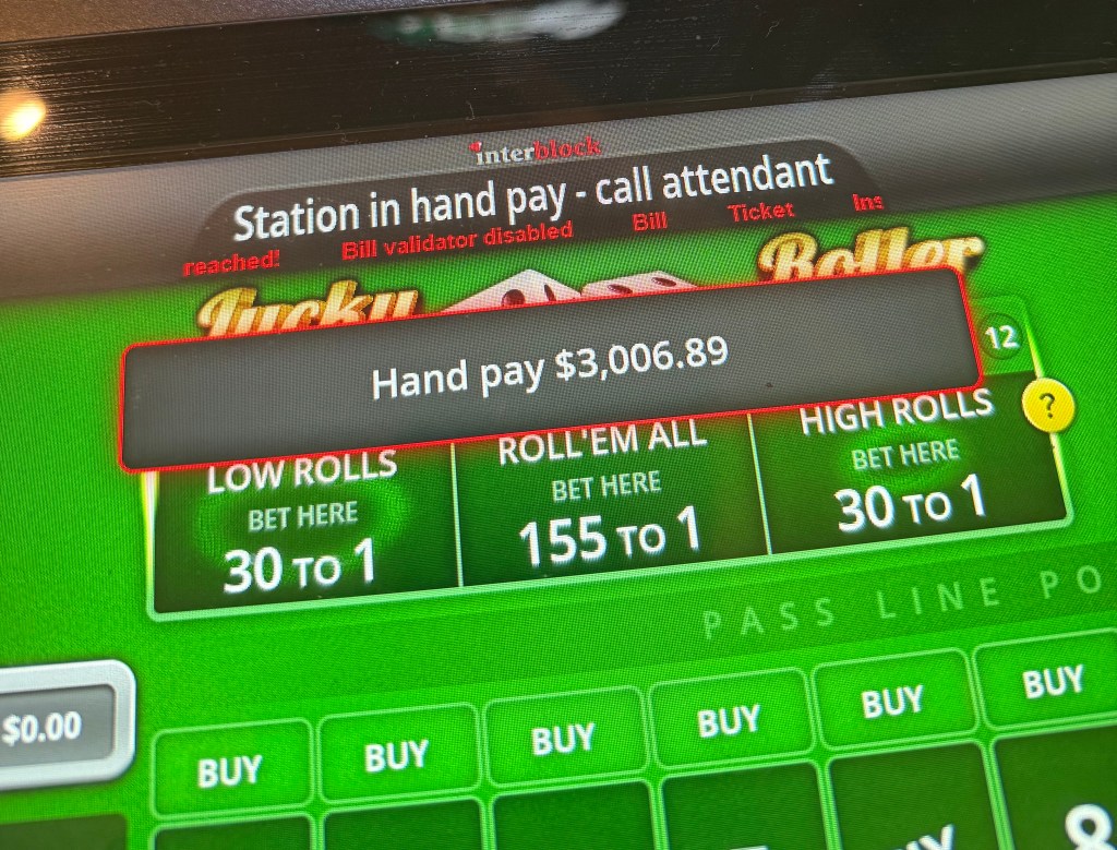 Display screen showing a hand pay amount of $3,006.89 for a craps game with betting options for low rolls, high rolls, and 'Roll'em All' on a green background.
